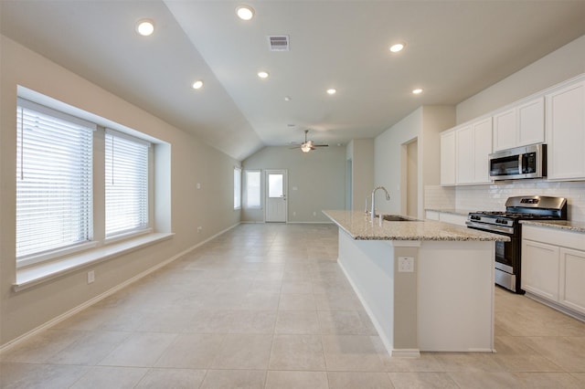 32014 Quail Terrace Ln, Conroe, TX 77385 - kitchen with stainless steel appliances, backsplash, an island with sink, ceiling fan, and light tile patterned floors