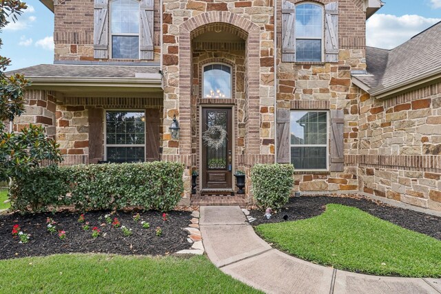 15521 Atwood Bay Trl, Cypress, TX 77433 - view of exterior entry with stone siding, brick siding, and a shingled roof