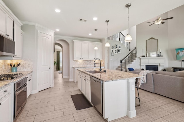 15521 Atwood Bay Trl, Cypress, TX 77433 - kitchen featuring stainless steel appliances, arched walkways, open floor plan, a ceiling fan, and white cabinetry