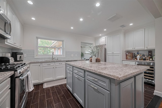 1931 Ansbury Dr, Houston, TX 77018 - kitchen with appliances with stainless steel finishes, beverage cooler, gray cabinets, white cabinets, and a center island