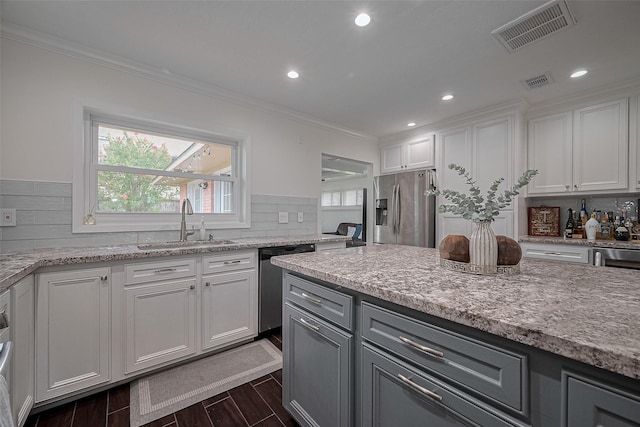 1931 Ansbury Dr, Houston, TX 77018 - kitchen with appliances with stainless steel finishes, decorative backsplash, white cabinets, ornamental molding, and dark wood-type flooring