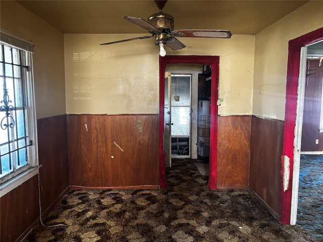 4124 Dabney St, Houston, TX 77026 - spare room featuring a wainscoted wall, ceiling fan, wooden walls, and water heater
