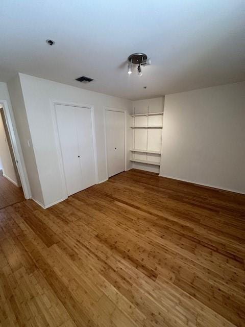40 N Interstate 35 Unit 3D3, Austin, TX 78701 - unfurnished bedroom featuring wood finished floors and multiple closets