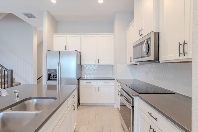 11016 Crescent Light Way, Houston, TX 77043 - kitchen featuring appliances with stainless steel finishes, white cabinets, decorative backsplash, recessed lighting, and dark countertops