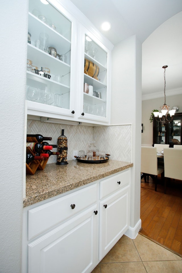 9303 Georgetown Glen Cir, Cypress, TX 77433 - bar area with crown molding, tasteful backsplash, light tile patterned flooring, a chandelier, and pendant lighting