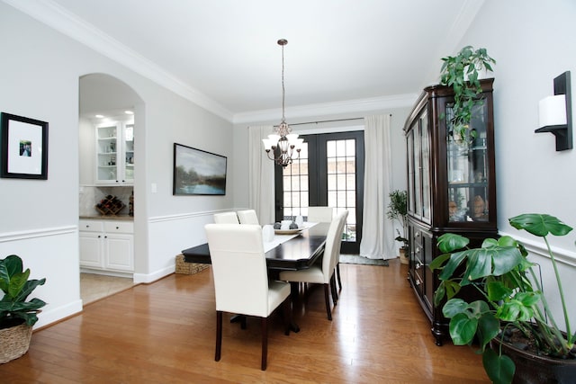 9303 Georgetown Glen Cir, Cypress, TX 77433 - dining room featuring light wood-type flooring, crown molding, arched walkways, and a chandelier
