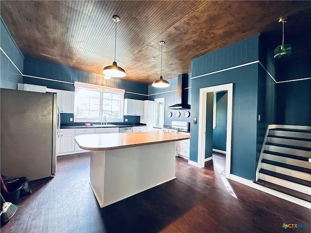 1002 E Gonzales St, Yoakum, TX 77995 - kitchen with appliances with stainless steel finishes, white cabinets, wall chimney exhaust hood, and dark wood finished floors