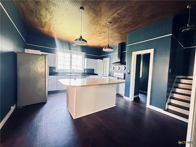 1002 E Gonzales St, Yoakum, TX 77995 - kitchen featuring appliances with stainless steel finishes, wall chimney range hood, a center island, dark wood-style flooring, and white cabinets