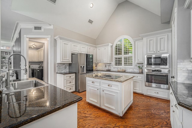 13602 Springmint Dr, Cypress, TX 77429 - kitchen featuring appliances with stainless steel finishes, white cabinets, decorative backsplash, high vaulted ceiling, and a center island