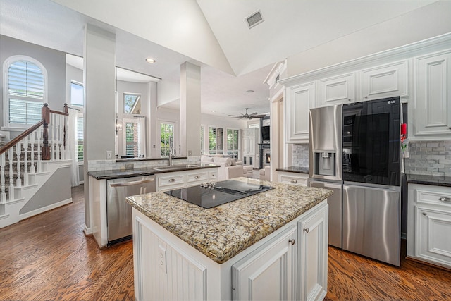 13602 Springmint Dr, Cypress, TX 77429 - kitchen with appliances with stainless steel finishes, a center island, backsplash, dark wood-type flooring, and dark stone countertops
