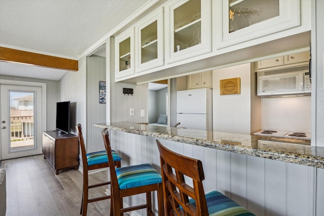 4014 2nd St, Galveston, TX 77554 - kitchen with white appliances, light wood finished floors, glass insert cabinets, and light stone counters