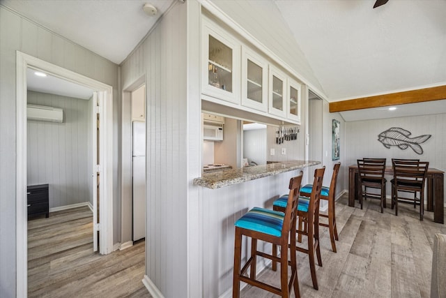 4014 2nd St, Galveston, TX 77554 - kitchen featuring light wood finished floors, an AC wall unit, white appliances, glass insert cabinets, and light stone countertops