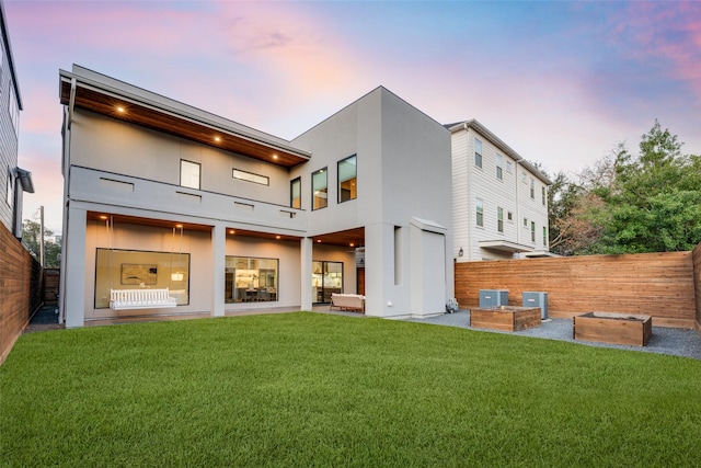 909 Peden St, Houston, TX 77006 - back of house at dusk with stucco siding, a balcony, and a fenced backyard