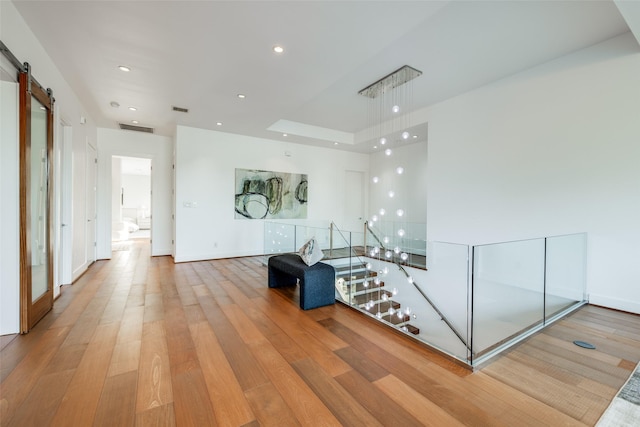 909 Peden St, Houston, TX 77006 - hall with light wood-style flooring, a barn door, and recessed lighting