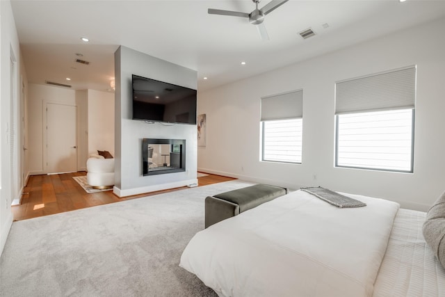 909 Peden St, Houston, TX 77006 - carpeted bedroom featuring a multi sided fireplace, wood finished floors, recessed lighting, and a ceiling fan