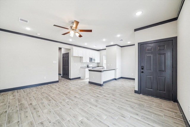9412 Crofton St, Houston, TX 77016 - kitchen featuring stainless steel microwave, ornamental molding, white cabinetry, a peninsula, and a ceiling fan