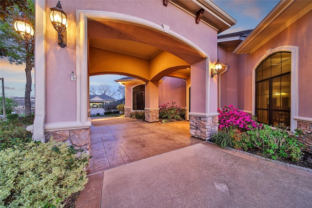 12540 Longmire Lakeview, Conroe, TX 77304 - exterior entry at dusk featuring stucco siding, stone siding, and a patio area