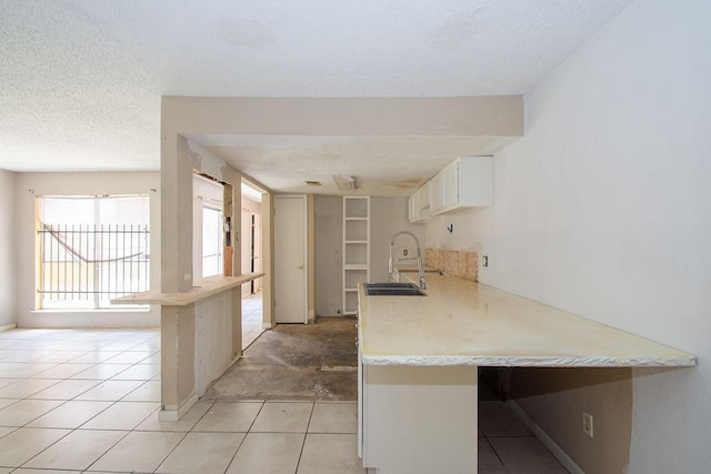 12254 Wild Pine Dr Unit A, Houston, TX 77039 - kitchen featuring a peninsula, light countertops, white cabinetry, a textured ceiling, and a kitchen breakfast bar