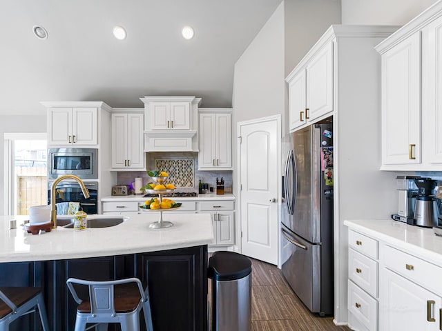 4006 Trento Ct, Katy, TX 77493 - kitchen with stainless steel appliances, a breakfast bar, white cabinetry, backsplash, and dark wood finished floors