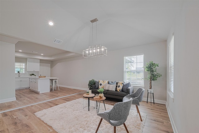 3514 Fuqua St, Houston, TX 77047 - living area with a chandelier, light wood-style flooring, vaulted ceiling, and a raised ceiling