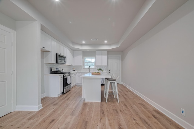3514 Fuqua St, Houston, TX 77047 - kitchen with stainless steel appliances, backsplash, a kitchen bar, white cabinetry, and light countertops