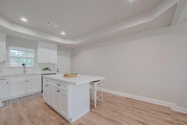 3514 Fuqua St, Houston, TX 77047 - kitchen featuring a breakfast bar, a raised ceiling, a center island, tasteful backsplash, and light wood finished floors