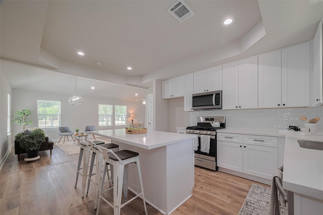 3514 Fuqua St, Houston, TX 77047 - kitchen with stainless steel appliances, light wood-style floors, a center island, light countertops, and decorative backsplash