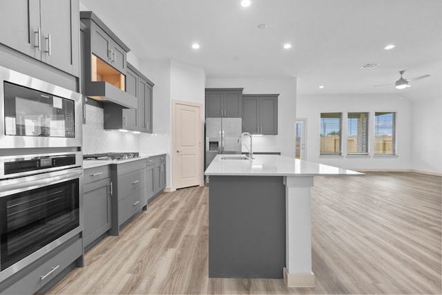 6226 Pelican Ridge Way, League City, TX 77573 - kitchen with gray cabinetry, light wood finished floors, appliances with stainless steel finishes, open floor plan, and light countertops