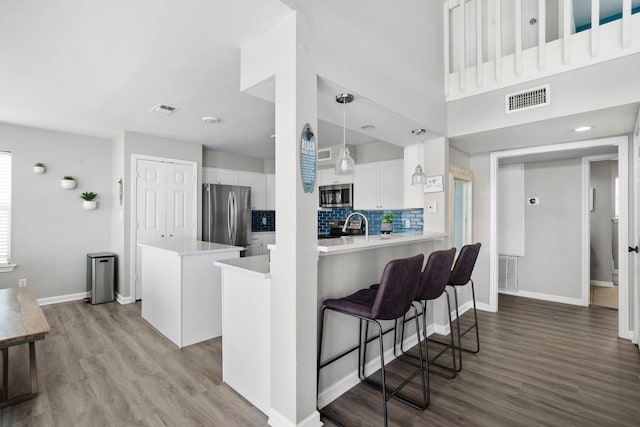 23401 Termini San Luis Pass Rd, Galveston, TX 77554 - kitchen with wood finished floors, white cabinetry, light countertops, a center island, and decorative backsplash