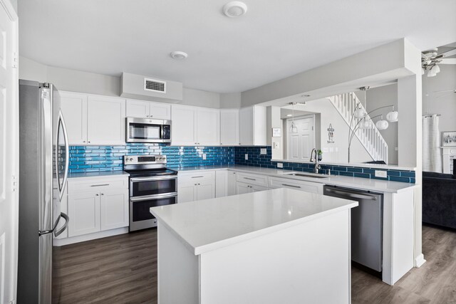 23401 Termini San Luis Pass Rd, Galveston, TX 77554 - kitchen with appliances with stainless steel finishes, dark wood-type flooring, backsplash, a kitchen island, and light countertops