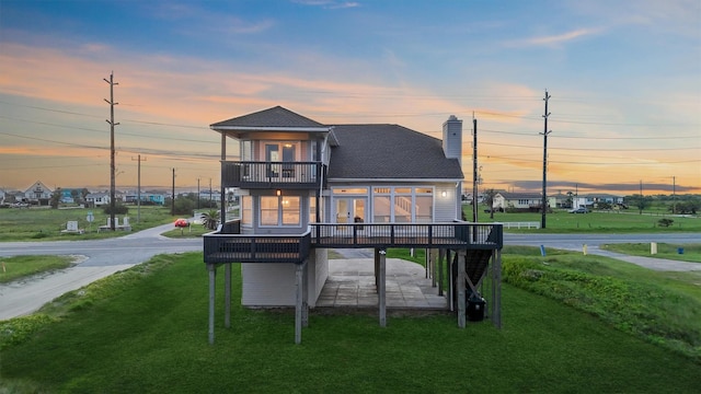 23401 Termini San Luis Pass Rd, Galveston, TX 77554 - rear view of house featuring a balcony, a lawn, a wooden deck, a chimney, and a carport