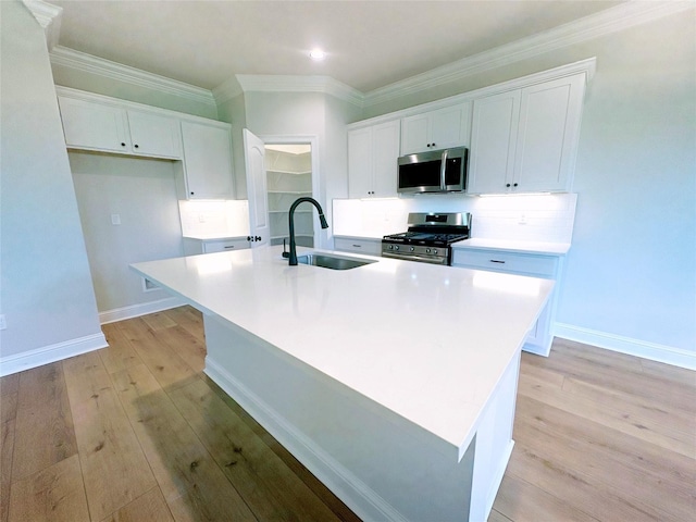 6715 Arbor Way, Orange, TX 77630 - kitchen with stainless steel appliances, white cabinets, light wood-style flooring, a center island with sink, and decorative backsplash