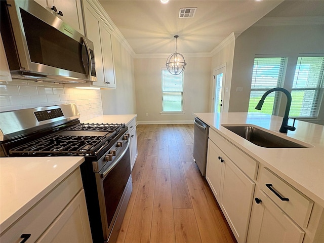 6715 Arbor Way, Orange, TX 77630 - kitchen with stainless steel appliances, crown molding, healthy amount of natural light, a chandelier, and light wood-style flooring