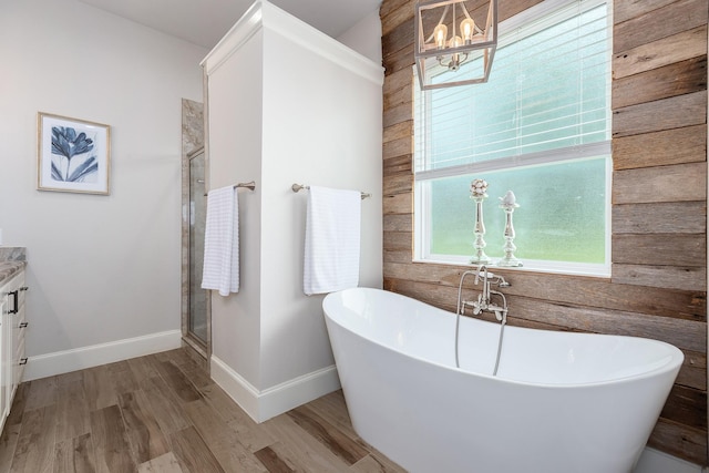27647 N Salado Ct, Splendora, TX 77372 - bathroom with a chandelier, wood finished floors, a freestanding tub, vanity, and wooden walls