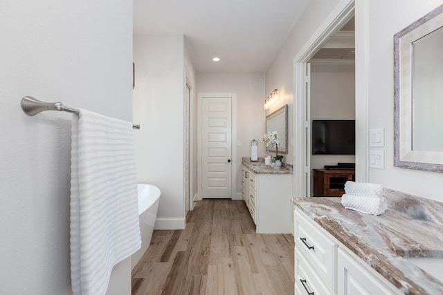 27647 N Salado Ct, Splendora, TX 77372 - bathroom featuring wood finished floors, two vanities, a freestanding bath, and recessed lighting