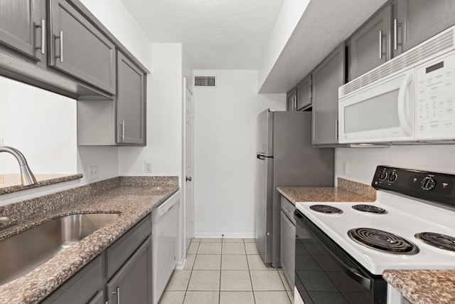 2120 El Paseo St Unit 2206, Houston, TX 77054 - kitchen with white appliances, gray cabinetry, light tile patterned floors, dark stone counters, and a textured ceiling