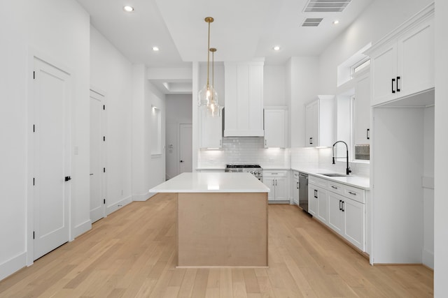 822 E 25th St, Houston, TX 77009 - kitchen featuring appliances with stainless steel finishes, backsplash, light wood finished floors, white cabinets, and a center island