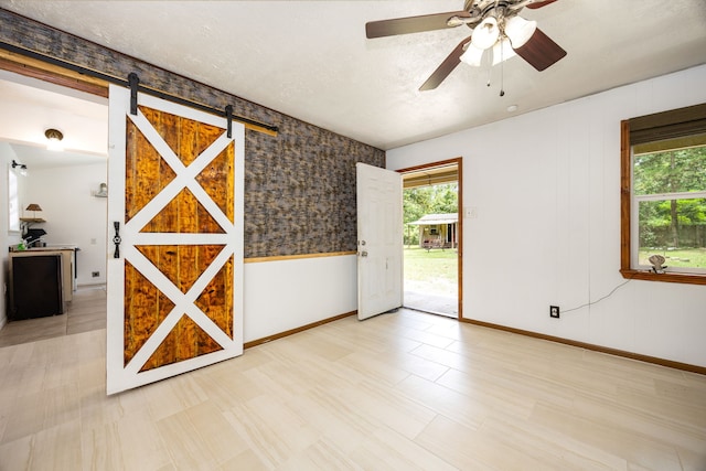 125 James Blvd, Livingston, TX 77351 - empty room featuring plenty of natural light, a barn door, ceiling fan, and wallpapered walls
