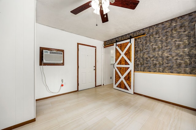 125 James Blvd, Livingston, TX 77351 - empty room featuring a ceiling fan, an AC wall unit, and a barn door