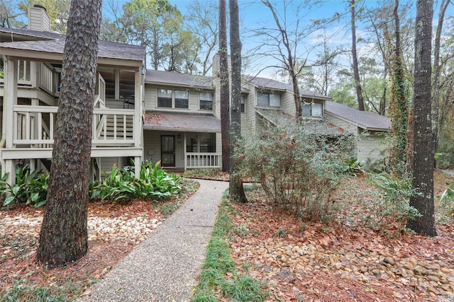 28 Sawmill Grove Ln, The Woodlands, TX 77380 - view of front of house with a shingled roof, a chimney, and a sunroom