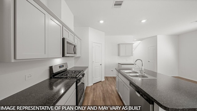 5434 Magnolia Heath Ln, Spring, TX 77373 - kitchen with appliances with stainless steel finishes, wood finished floors, recessed lighting, and a kitchen island with sink
