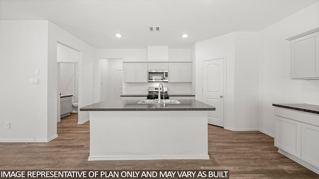 5434 Magnolia Heath Ln, Spring, TX 77373 - kitchen with stainless steel microwave, wood finished floors, recessed lighting, white cabinetry, and an island with sink