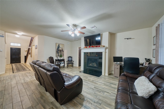 4719 Echo Bay Dr, Baytown, TX 77523 - living room with light wood finished floors, a tile fireplace, a ceiling fan, an office area, and a textured ceiling