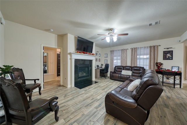 4719 Echo Bay Dr, Baytown, TX 77523 - living area with a tiled fireplace, ceiling fan, light wood finished floors, and a textured ceiling
