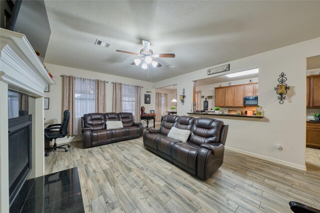 4719 Echo Bay Dr, Baytown, TX 77523 - living room featuring a ceiling fan, light wood-style flooring, a desk, and a textured ceiling