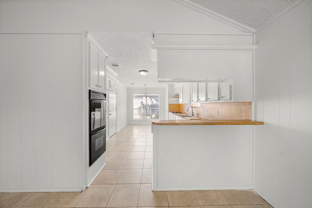 1517 Van Buren Dr, Deer Park, TX 77536 - kitchen featuring a textured ceiling, white cabinetry, light tile patterned flooring, a peninsula, and lofted ceiling