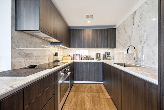 1701 Hermann Dr Unit 23B, Houston, TX 77004 - kitchen with oven, decorative backsplash, modern cabinets, and dark brown cabinets
