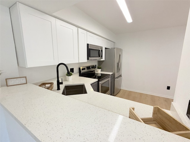 9090 S Braeswood Blvd Unit 115, Houston, TX 77074 - kitchen with appliances with stainless steel finishes, light wood finished floors, light stone countertops, white cabinetry, and a peninsula
