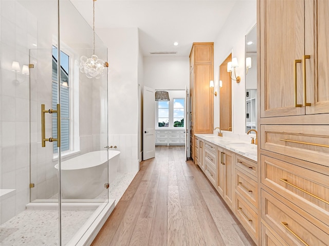 430 81st St, Galveston, TX 77554 - bathroom with double vanity, a soaking tub, a stall shower, wood-type flooring, and a chandelier
