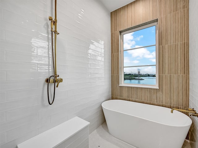 430 81st St, Galveston, TX 77554 - bathroom featuring tile walls, a soaking tub, and a water view